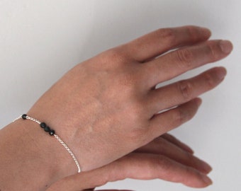 Peut inclure: Un bracelet en chaîne argent avec des perles noires.