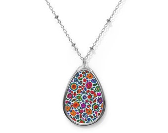 Puede incluir: Un collar de cadena de plata con un colgante en forma de lágrima con un estampado floral colorido.