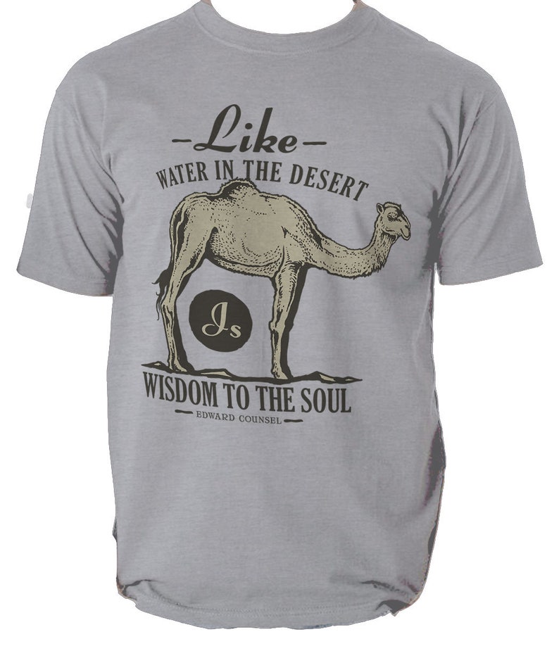 K&ouml;nnte beinhalten: Hellgraues T-Shirt mit Kamel-Illustration und dem Text "Wie Wasser in der W&uuml;ste, Weisheit f&uuml;r die Seele". Das Design enth&auml;lt die Initialen "Js" in einem Kreis und den Namen "Edward Counsel".