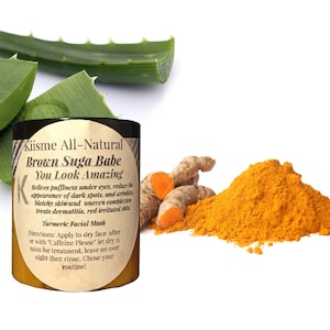 Puede incluir: Un tarro amarillo de mascarilla facial de cúrcuma Kiisme All-Natural Brown Suga Babe You Look Amazing. El tarro está etiquetado con instrucciones de uso. El tarro está rodeado de hojas frescas de aloe vera y polvo de cúrcuma.