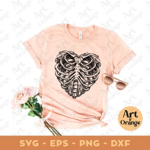 May include: A pink t-shirt with a black and white illustration of a ribcage in the shape of a heart. The text "Art of Orange" is in a circle on the bottom right corner of the image.