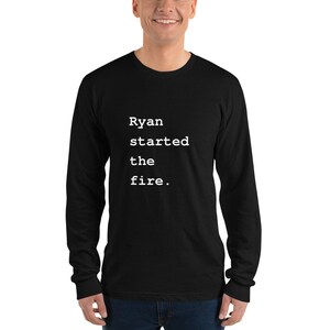 May include: Black long-sleeve t-shirt with white text that reads "Ryan started the fire."