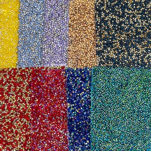 May include: A close-up of a variety of colorful rhinestone fabrics. The fabrics are arranged in rows and feature different colors, including gold, blue, red, green, and purple.