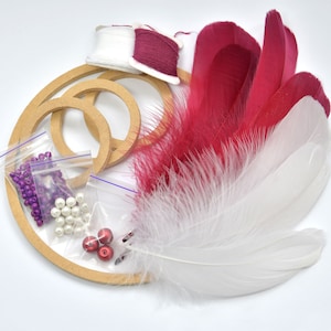 May include: A craft kit for making a dream catcher with wooden hoops, white and red feathers, purple and white beads, and red and white string.
