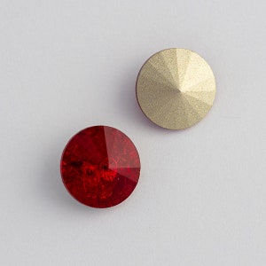 May include: Two round, flat-backed rhinestones. One is a gold color and the other is a deep red.