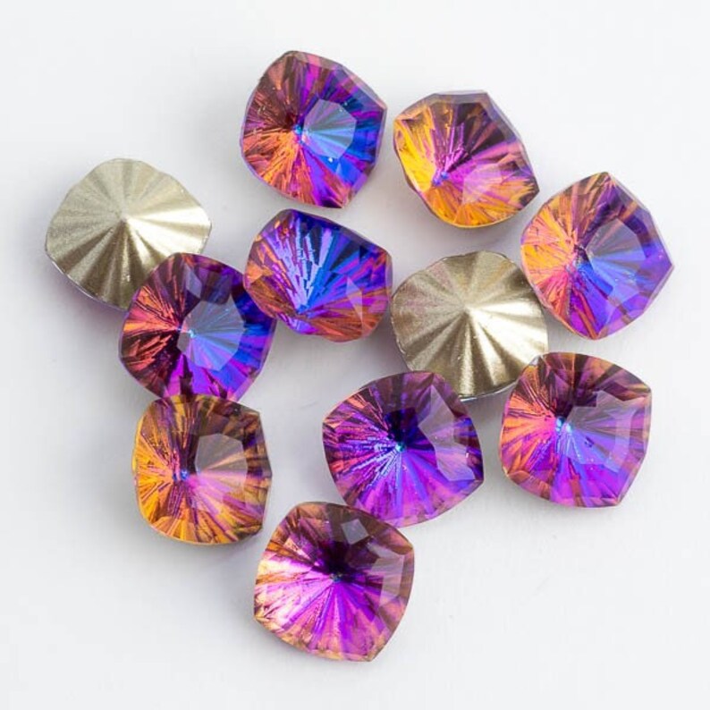 May include: Assortment of iridescent purple and orange square-shaped rhinestones with a faceted design.