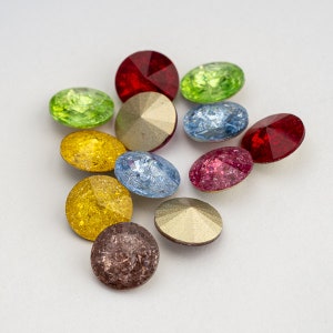 May include: Assortment of round, flat-backed rhinestones in various colors, including red, green, blue, gold, and pink. The rhinestones have a faceted, sparkly finish.