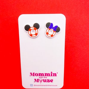 Puede incluir: Un par de pendientes de bot&oacute;n blancos con orejas de Mickey Mouse rojas, blancas y negras y un salvavidas rojo, blanco y negro. Los pendientes est&aacute;n en una tarjeta blanca con el texto "Mommin' with the Mouse" y el nombre de usuario de Instagram "@momminwiththemouse".