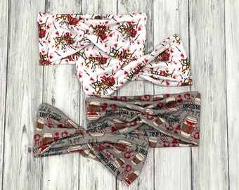 May include: Three gray and white fabric headbands with a true crime theme. One headband has a coffee cup design with the text "fueled by coffee & true crime". The other two headbands have a white background with red splatter and the text "true crime is just" repeated.
