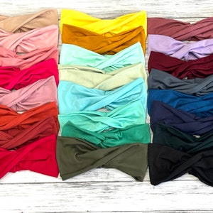 May include: A collection of 15 twisted headbands in various colours, including beige, yellow, mustard, green, blue, red, and black. The headbands are made of a soft, stretchy fabric and are perfect for adding a pop of colour to any outfit.