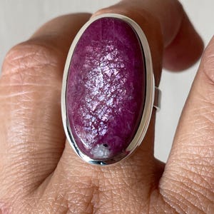 Puede incluir: Un anillo de plata con una gran piedra preciosa ovalada de color rosa engastada en un engaste de plata.
