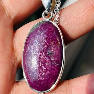 May include: A silver chain necklace with a large oval pendant featuring a pink and green gemstone. The pendant is set in a silver bezel.