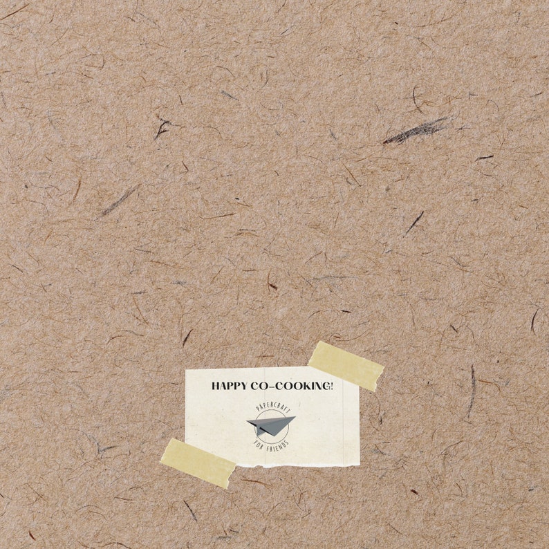 May include: A tan paper background with a yellow sticky note attached to it. The note says "HAPPY CO-COOKING!" and has a small black and white logo with a paper airplane and the text "PAPERCRAFT FOR FRIENDS".