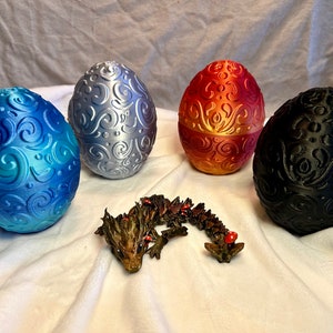 May include: Four intricately patterned dragon eggs in blue, silver, red, and black, with a small brown dragon figurine in the center.