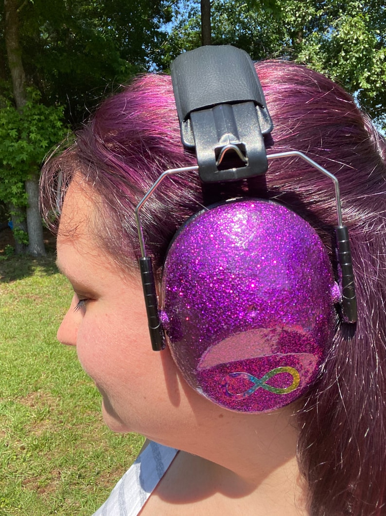 May include: Purple earmuffs with a rainbow infinity symbol on the side. The earmuffs are covered in glitter.