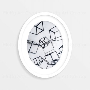 May include: A white framed photograph of a white room with black wire cubes hanging from the ceiling.