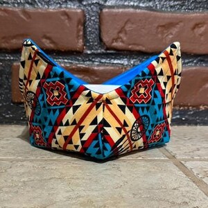 May include: A small, blue and beige fabric bowl with a geometric pattern. The bowl is folded and has a pointed shape.