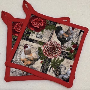 May include: Two red and white quilted pot holders with a rooster, floral, and vintage letter design.