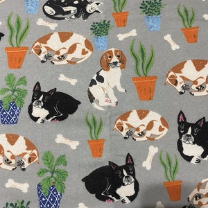 May include: A grey fabric with a repeating pattern of dogs and potted plants. The dogs are in various poses, including sleeping, sitting, and standing. The plants are in terracotta pots with green leaves. There are also white bone shapes scattered throughout the pattern.