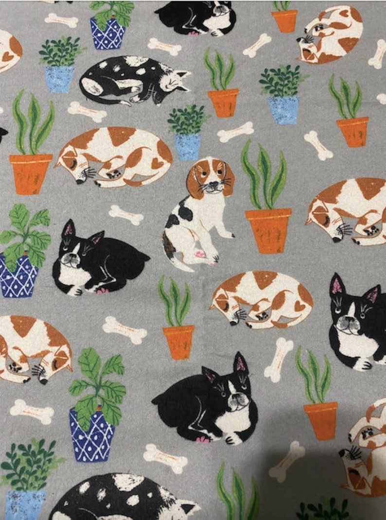 May include: A grey fabric with a repeating pattern of dogs and potted plants. The dogs are in various poses, including sleeping, sitting, and standing. The plants are in terracotta pots with green leaves. There are also white bone shapes scattered throughout the pattern.