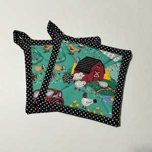 May include: Two green and black quilted pot holders with a farm scene featuring a red barn, chickens, sheep, and a tractor. The pot holders have a black and white polka dot border.