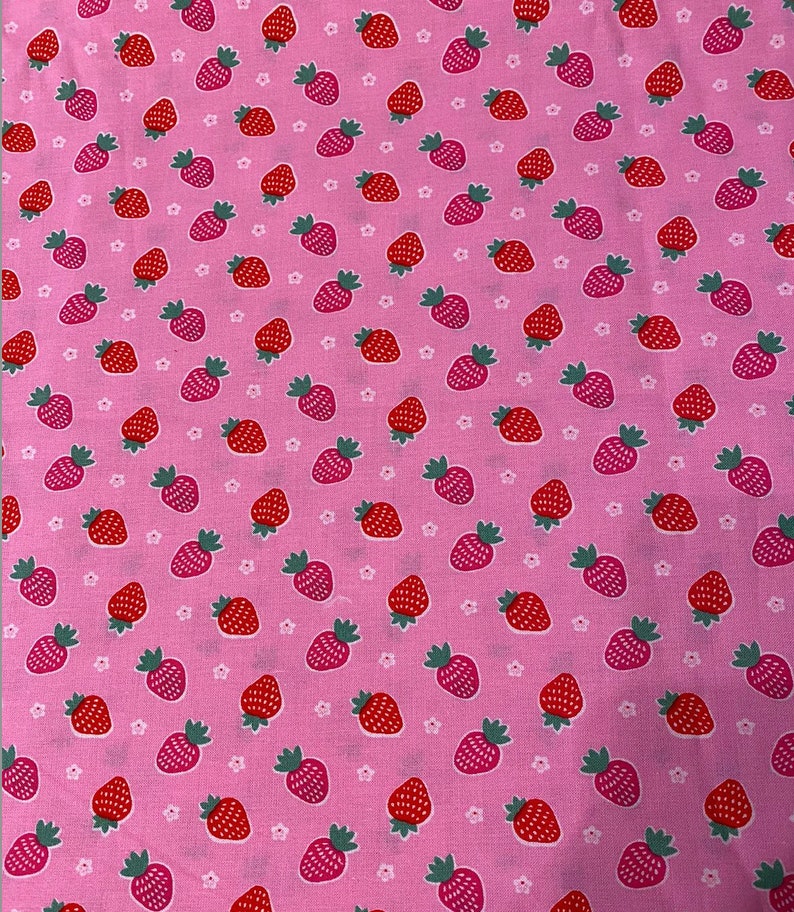 Puede incluir: Tela rosa con un patr&oacute;n repetido de fresas rojas y estrellas blancas de cinco puntas.