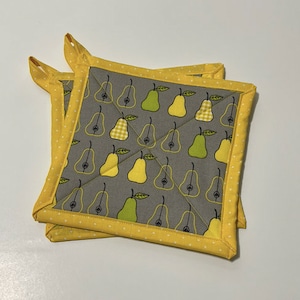May include: Two gray and yellow quilted pot holders with a pear pattern. The pot holders have a yellow border with white polka dots.