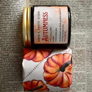 Könnte beinhalten: Ein Glaskerzenglas mit goldenem Deckel und einem Etikett mit der Aufschrift BARVA A POETIC STUDIO AUTUMNESS, walnut, pecan, coffee, pumpkin, caramel, warm spice, soy and coconut wax blend, premium fragrance oil, burn time: around 25 hrs, BARVASTUDIO.COM.