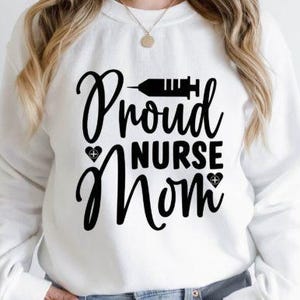 May include: A white sweatshirt featuring the black text "Proud Nurse Mom" with a syringe graphic and heart details. This casual top is a comfortable style.