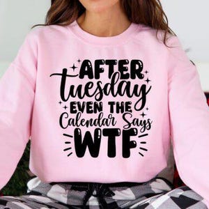 May include: A light pink sweatshirt with long sleeves. The front of the sweatshirt features the black text "AFTER Tuesday EVEN THE Calendar Says WTF". The sweatshirt is part of a clothing collection.