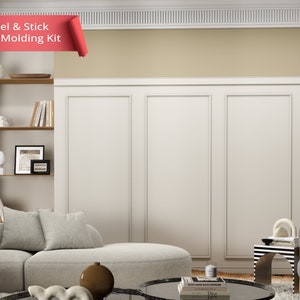 Puede incluir: Un interior de sala de estar con un kit de molduras de pared blancas instalado en la pared. La moldura es un diseño de pelar y pegar. El texto "Peel & Stick Wall Molding Kit" es visible en la imagen.