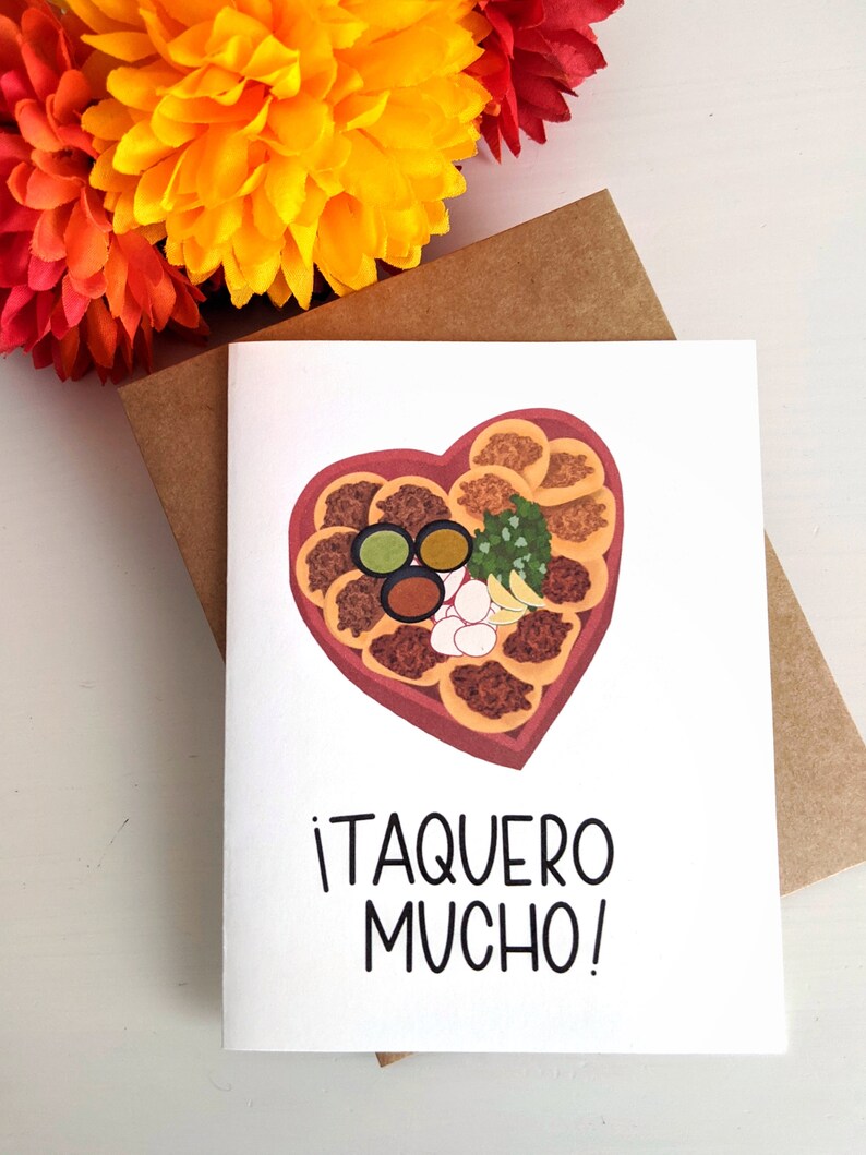 May include: A white card with a heart-shaped illustration of a taco platter with toppings. The text on the card reads "&iexcl;Taquero Mucho!"