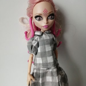 May include: A pink-haired doll with a gray and white checkered dress. The doll has pink eyes and a pink diamond-shaped design on her forehead.