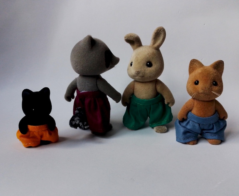 May include: Four plush toy animals wearing pants. A black cat wearing orange pants, a raccoon wearing burgundy pants, a brown rabbit wearing green pants, and an orange cat wearing blue pants.