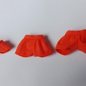 May include: Three pairs of orange shorts in different sizes. The shorts are made of a soft, comfortable fabric and have a simple design.
