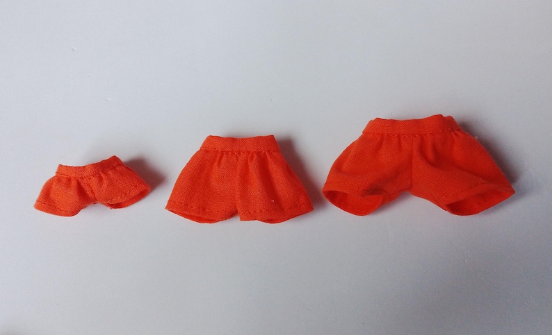May include: Three pairs of orange shorts in different sizes. The shorts are made of a soft, comfortable fabric and have a simple design.