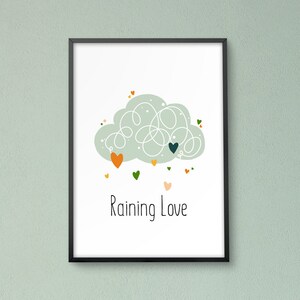 Puede incluir: Una impresión enmarcada en negro con una nube blanca y corazones en tonos de verde, naranja y rosa. El texto "Raining Love" está escrito debajo de la nube.