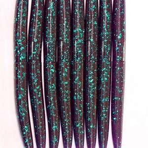 May include: A group of ten purple and teal glitter worm fishing lures.