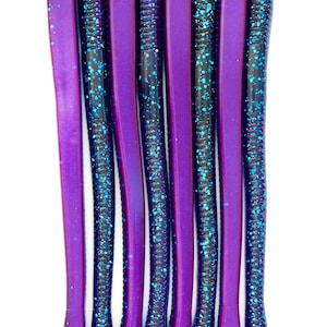 May include: Eight purple and blue fishing lures with glitter. The lures are long and slender with a pointed end.