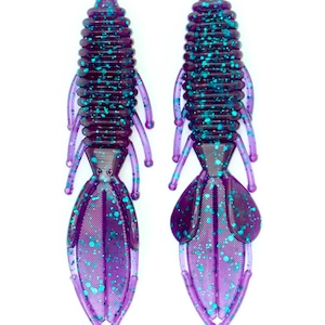 May include: Two purple and teal soft plastic fishing lures with a segmented body and a forked tail.