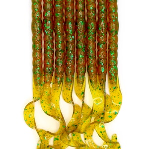 May include: A pack of ten green and brown fishing lures. The lures are made of soft plastic and have a curly tail.