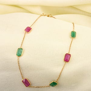 May include: A gold chain necklace with alternating pink and green rectangular gemstones.
