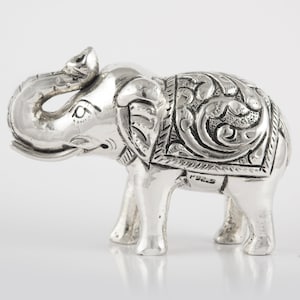 May include: A silver elephant figurine with intricate floral designs on its back. The elephant's trunk is curled up and the figurine is marked with "92.5" on the bottom.