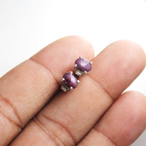 Op de afbeelding: Een paar zilveren oorbelletjes met ovale, paarse edelstenen.