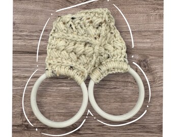Puede incluir: Un par de anillos de toalla de cerámica blanca con una cubierta de ganchillo beige. La cubierta tiene un patrón tejido texturizado.