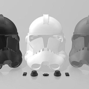 May include: Three plastic helmets in black, white, and gray. The helmets are detailed with a visor and a raised ridge on top. The helmets are arranged in a row on a gray background.