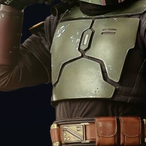 May include: A green and brown Mandalorian helmet with a visor. The helmet is worn by a person with a brown leather belt with a metal buckle. The belt has two pouches on the right side.