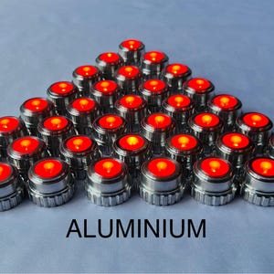May include: A collection of small, metallic, cylindrical objects with a bright red, illuminated top arranged in a pyramid shape. The word "ALUMINIUM" is printed in bold, black letters at the bottom.