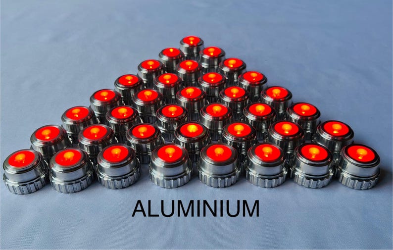 May include: A collection of small, metallic, cylindrical objects with a bright red, illuminated top arranged in a pyramid shape. The word "ALUMINIUM" is printed in bold, black letters at the bottom.