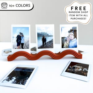 Könnte beinhalten: Ein wellenförmiger, orangefarbener Fotorahmen mit drei gerahmten Fotos. Die Fotos zeigen Menschen in der Natur. Zusätzliche Fotos sind darunter verstreut. Der Halter trägt den Text "10+ FARBEN".